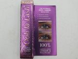 Le mascara se trouve à côté d'une boîte de mascara, posée sur une surface blanche.
