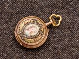 un gros plan d'une montre de poche en or sur laquelle figure le portrait d'une femme
