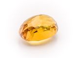 a close up of a yellow sapphire stone on a white surface