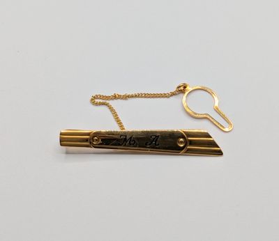 un gros plan d'un stylo muni d'une chaîne en or posé sur une surface blanche