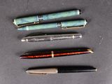 several pens are lined up on a table with a black background