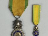 deux médailles sont représentées sur un fond blanc, ornées d'un ruban bleu et jaune