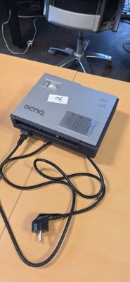 a laptop computer sitting on a table with a charger plugged into it