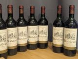 six bottles of wine are lined up on a wooden barrel