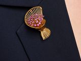 a close up of a brooch with pink flowers on it