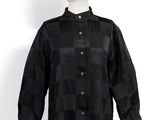 Le mannequin porte une chemise noire à carreaux.