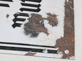 a rusted street sign on the wall of a building