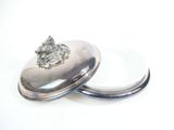 silver plate with a diamond on top of it sitting on a white surface