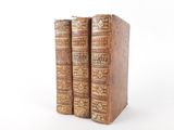 two old books sitting on top of each other on a white surface