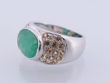 a close up of a ring with a green stone surrounded by diamonds