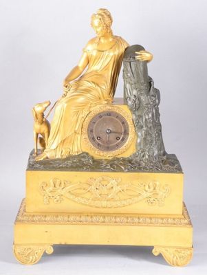 une horloge en or sur laquelle sont représentés une femme et un chien