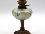 une lampe à huile ancienne posée sur un socle, sur fond blanc