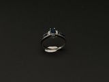 une photo d'une bague sertie d'un diamant et d'un saphir sur un fond noir