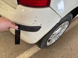 a person holding a remote control in front of a white car