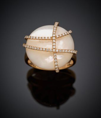 une bague en perles blanches et diamants sur une surface noire