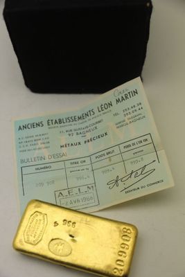 un lingot d'or posé à côté d'un sac à main noir sur une table