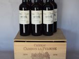 trois bouteilles de vin se trouvent dans une caisse en bois posée sur une table