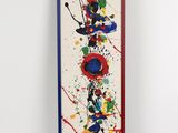 une peinture abstraite sur un mur blanc, encadrée d'une bordure rouge, bleue et jaune