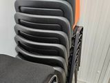a lot of black chairs in a room with orange walls