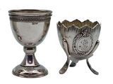 two silver cups sitting next to each other on a white surface