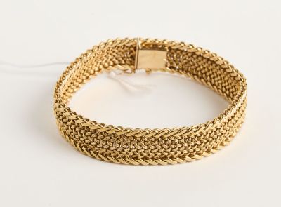 gros plan d'un bracelet en or sur une surface blanche