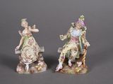 pair of porcelain figurines of a man and a woman sitting on a bench