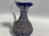 un pichet en verre bleu et blanc posé sur une table