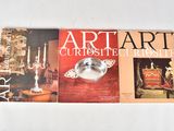 three books of art and antiques on display on a white surface