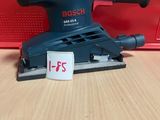 La ponceuse orbitale Bosch se trouve sur une table, à côté d'une boîte rouge