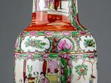 a red and white vase sitting on a wooden table