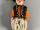 a small doll that is wearing a hat and orange pants