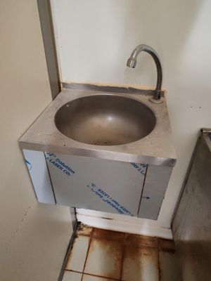 un lavabo dans un coin de la salle de bains, équipé d'un robinet en métal