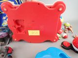 a red toy clock sitting on a table next to other toys