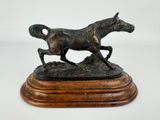 statue représentant un cheval et un poulain au galop, posée sur un socle en bois