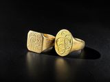 a pair of gold rings with initials on them on a black surface