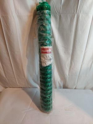 un tube en plastique vert, emballé dans du plastique, posé sur une surface blanche