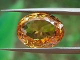 un gros plan d'un diamant jaune tenu par une paire de pinces