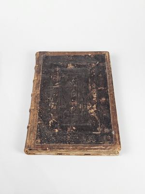 un vieux livre posé sur une table à côté d'un mur blanc