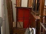a red cabinet in the corner of a room next to a stack of books