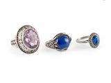 trois anneaux ornés de pierres violettes et bleues sur fond blanc