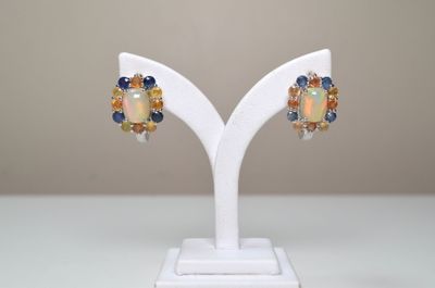 paire de boucles d'oreilles en oplite, saphir et citrine, présentées sur un socle blanc