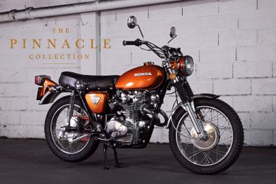 an orange motorcycle parked in front of a white brick wall