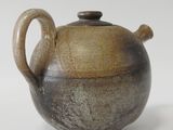 a brown and black teapot on a white surface
