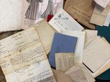 a pile of old papers on the floor next to a pile of books