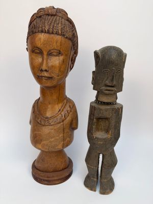 deux statues en bois représentant une femme et un homme sur fond blanc