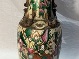 un vase orné d'une peinture posé sur une surface blanche