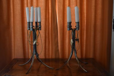 two candles that are sitting on a table in front of a curtain