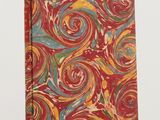 a red notebook with colorful swirls on it sitting on a white surface
