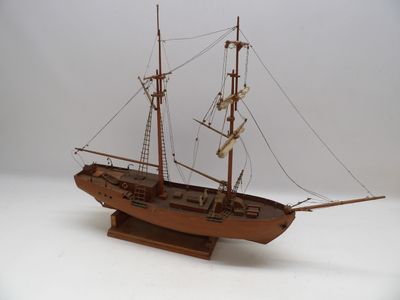 une maquette en bois d'un bateau posée sur une surface blanche