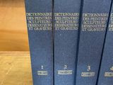 four blue books on a wooden table in front of a bookshelf